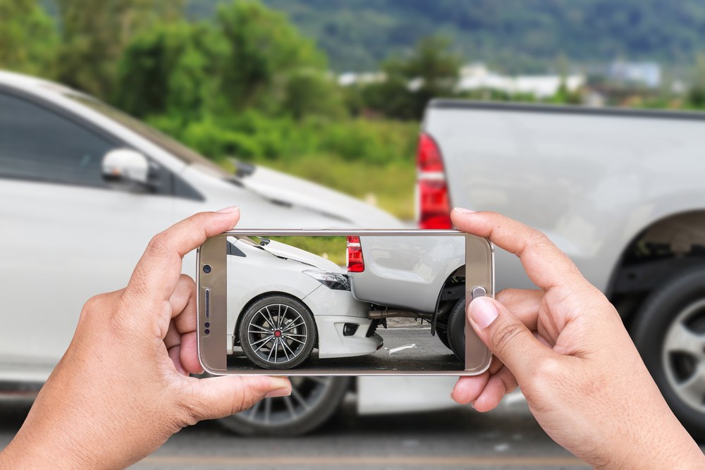 Hand of woman holding smartphone and take photo of car accident